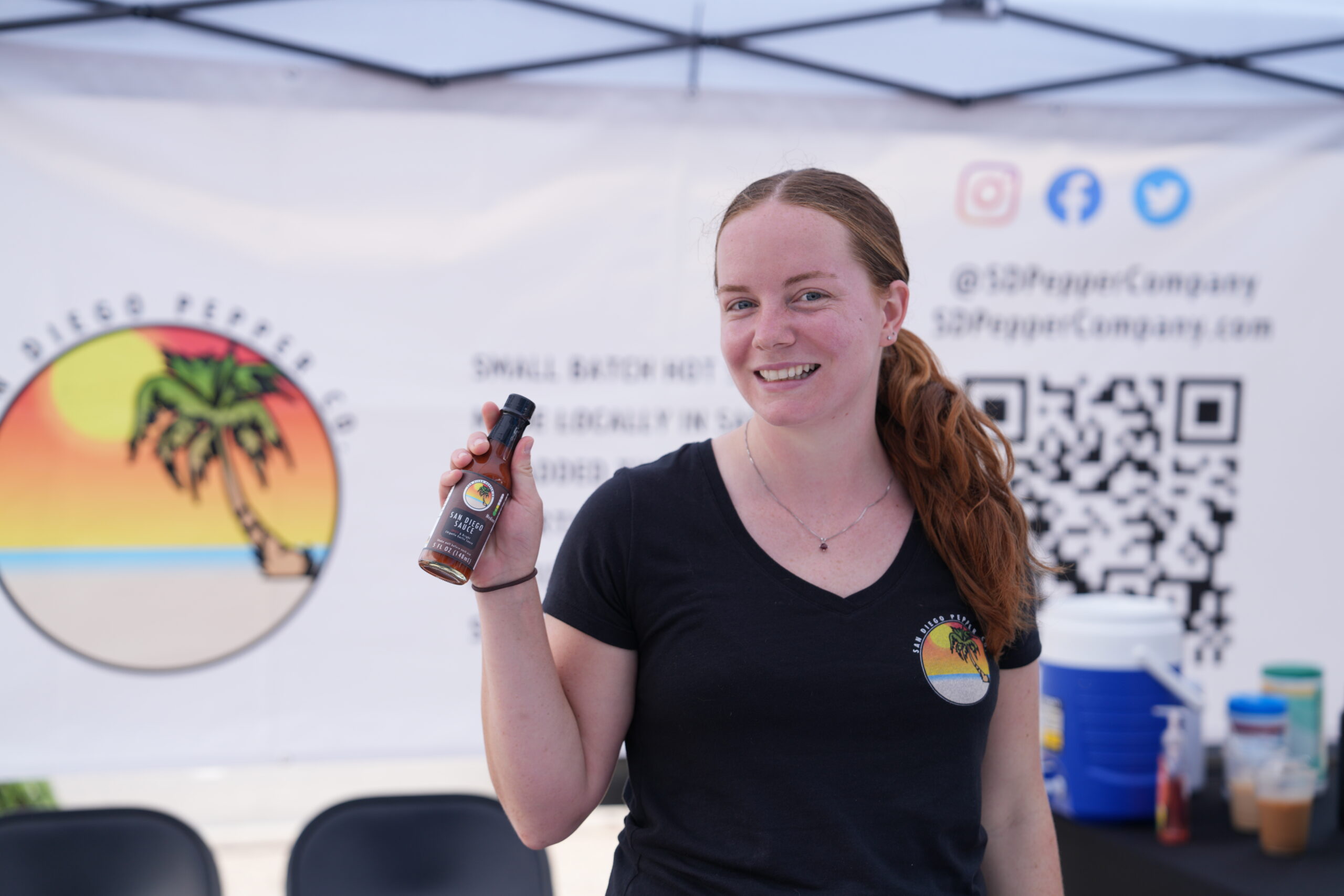 San Diego Pepper Company at the Point Loma farmers market holding an authentic bottle of San Diego sauce