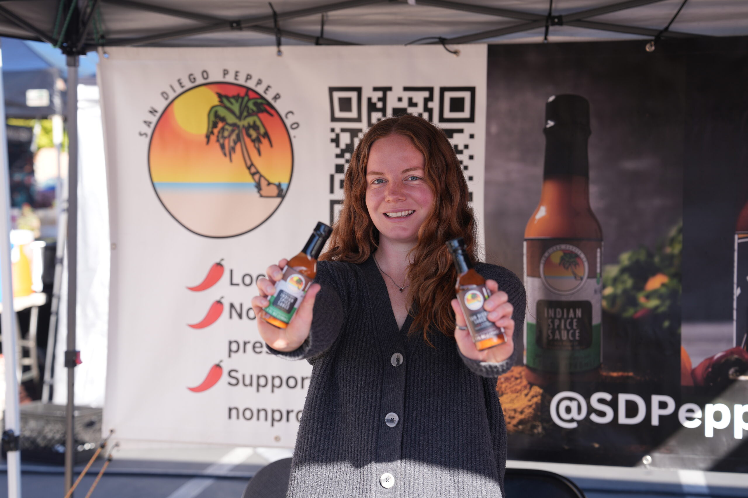 San Diego Pepper Company employee holding San Diego Sauce at the Solana Beach Farmers Farmet