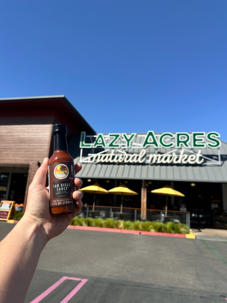 San Diego Sauce being held in front of Lazy Acres Market